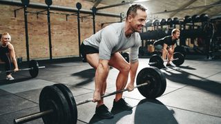 Three people doing a barbell deadlift during gym workout
