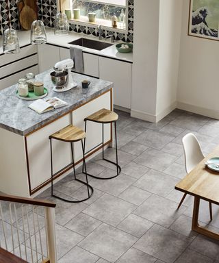 A kitchen with a concrete-effect gray vinyl floor laid in square tiles of two different sizes.