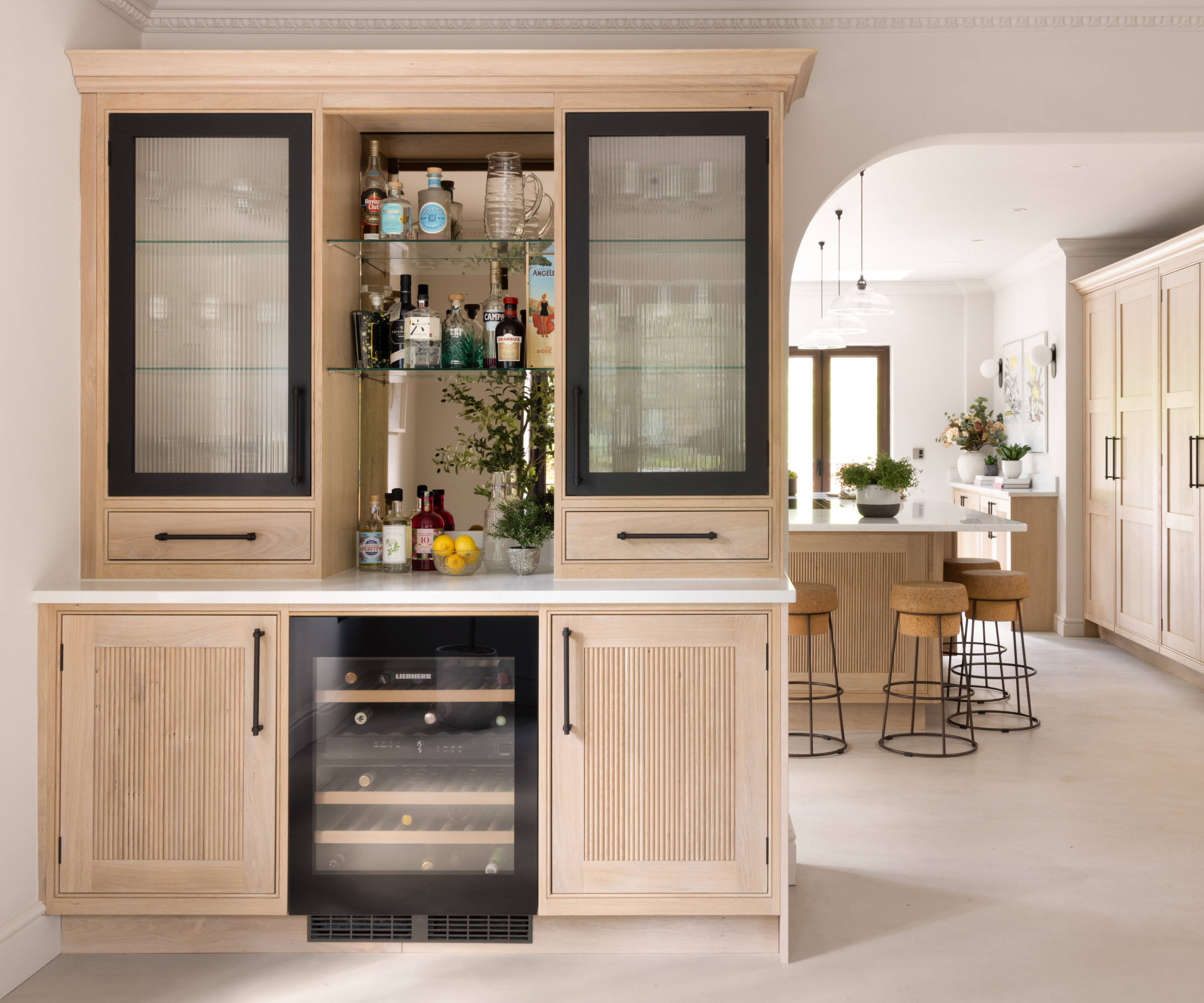 kitchen cabinets with open central section on top with bar set-up, closed cabinets to either side with wine fridge and cabinets below