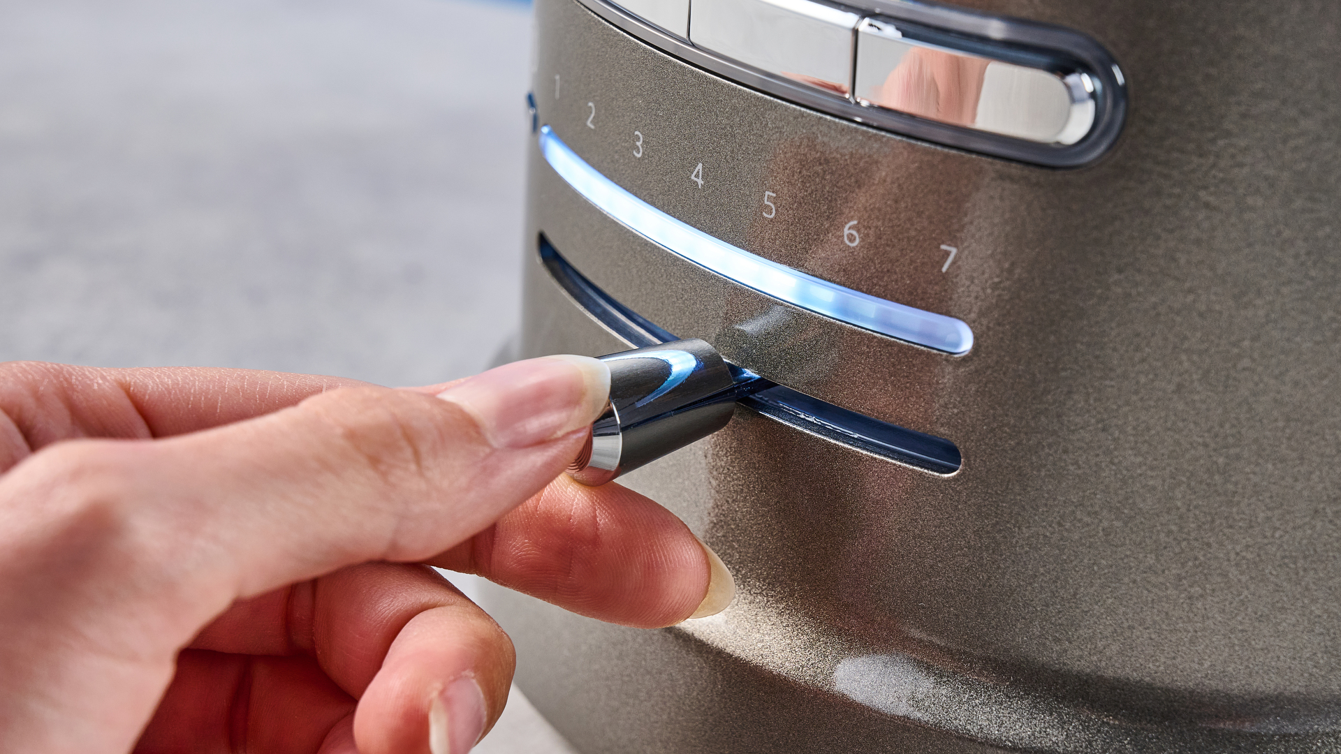 A photograph of the KitchenAid Pro Line toaster on a stone work surface with a blue and wooden background