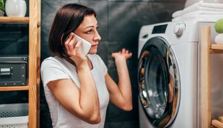 woman on phone in front of washing machine