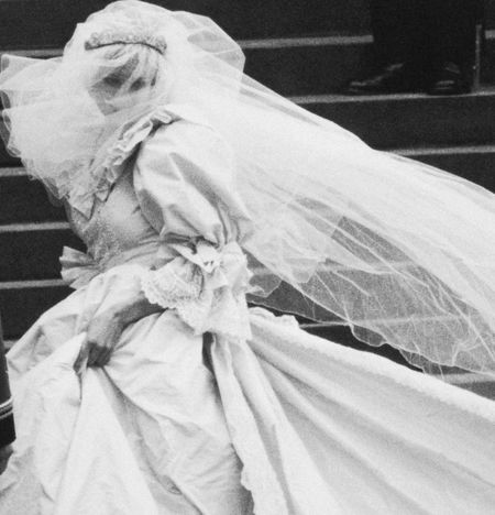 A black and white photo of Princess Diana walking up the stairs of St. Paul's Cathedral in her wedding dress in 1981