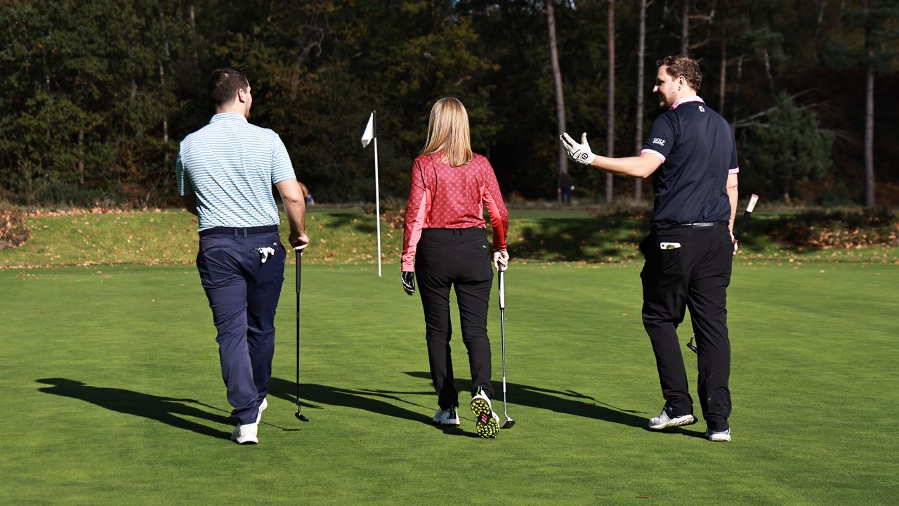 Three golfers walking and talking on a golf course