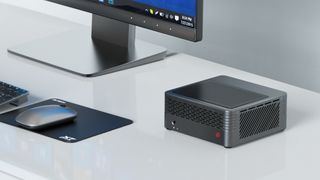 Mini-PC på hvidt bord med hjørne af monitor og mus på musemåtte