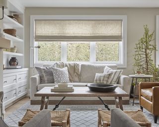 A neutral-toned living room with blue patterned rug, grey sofa and brown leather recliner