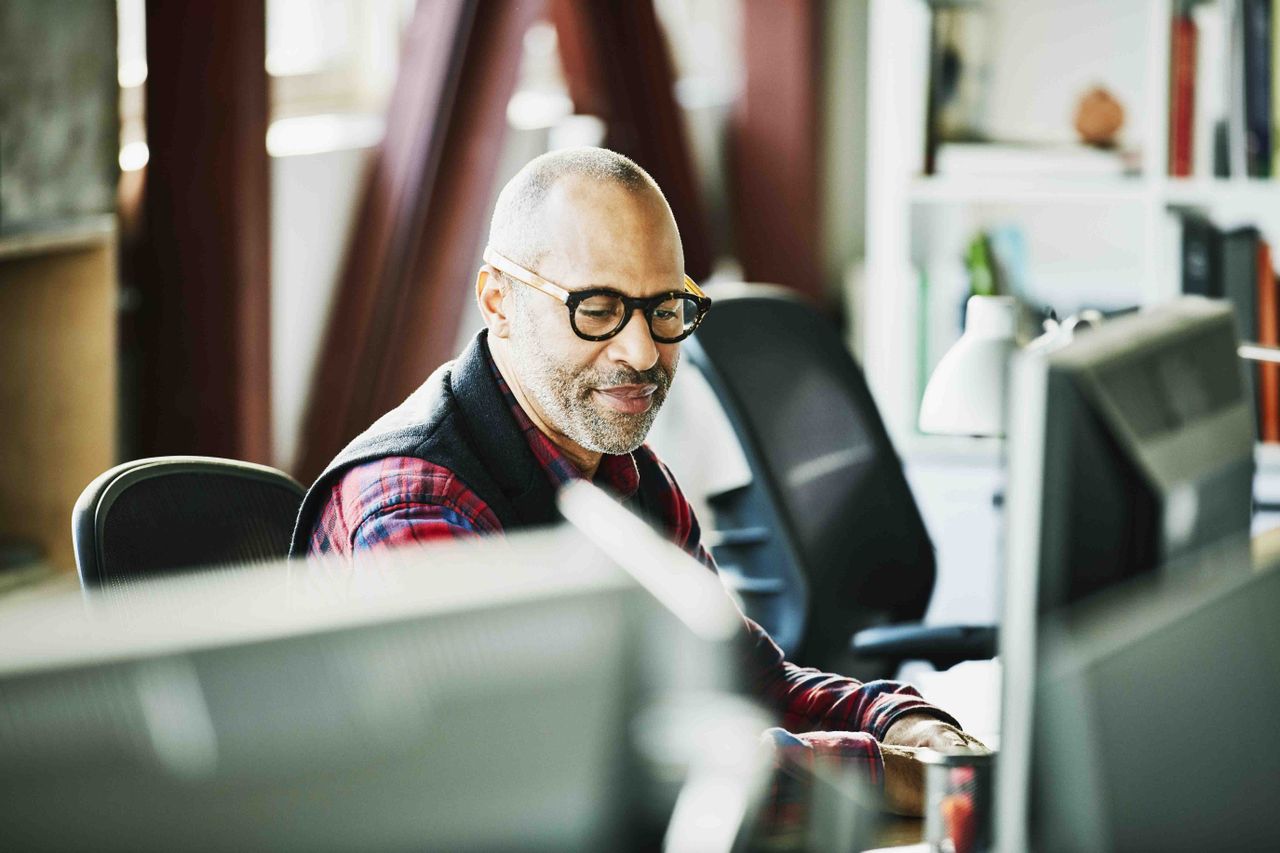 A man sitting at a desk looking at computer.