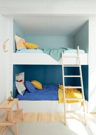 White bunk beds built into the wall with fun matching wall paint for each bed's bedcovers, illustrating clever shared bedroom ideas.