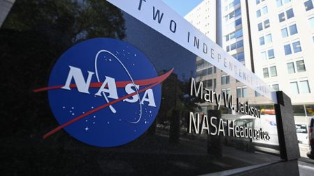 a black marble sign beside a city street reading "mary w. jackson nasa headquarters"