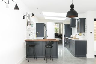 a small kitchen with charcoal grey wall panelling with island/peninsula and wood worktop with breakfast bar