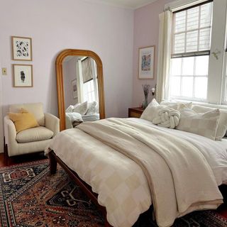 Neutral dressed bed in small lilac bedroom with full length wicker trim mirror