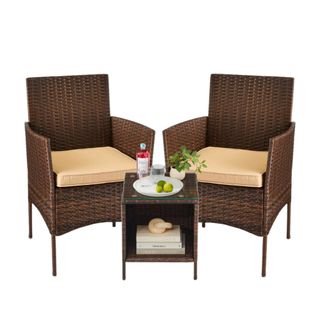 A brown wicker outdoor furniture set with two seats and a table with decor on it