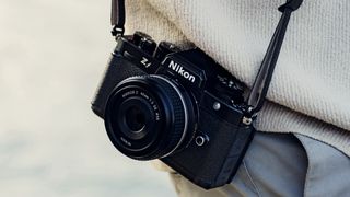 Nikon Zf with Z 40mm F2 lens attached on a strap by photographer's waist