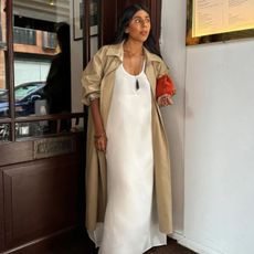 @monikh wearing a white shift dress and trench coat