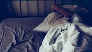 A woman lies in bed, unable to sleep due to insomnia