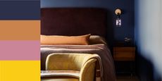a color combination with a navy blue bedroom with orange, pink, yellow and purple decor, as well as a brass wall lamp