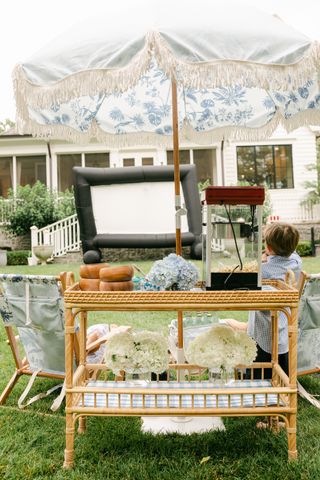 garden party with inflatable outdoor projector screen, popcorn maker, chairs, and table