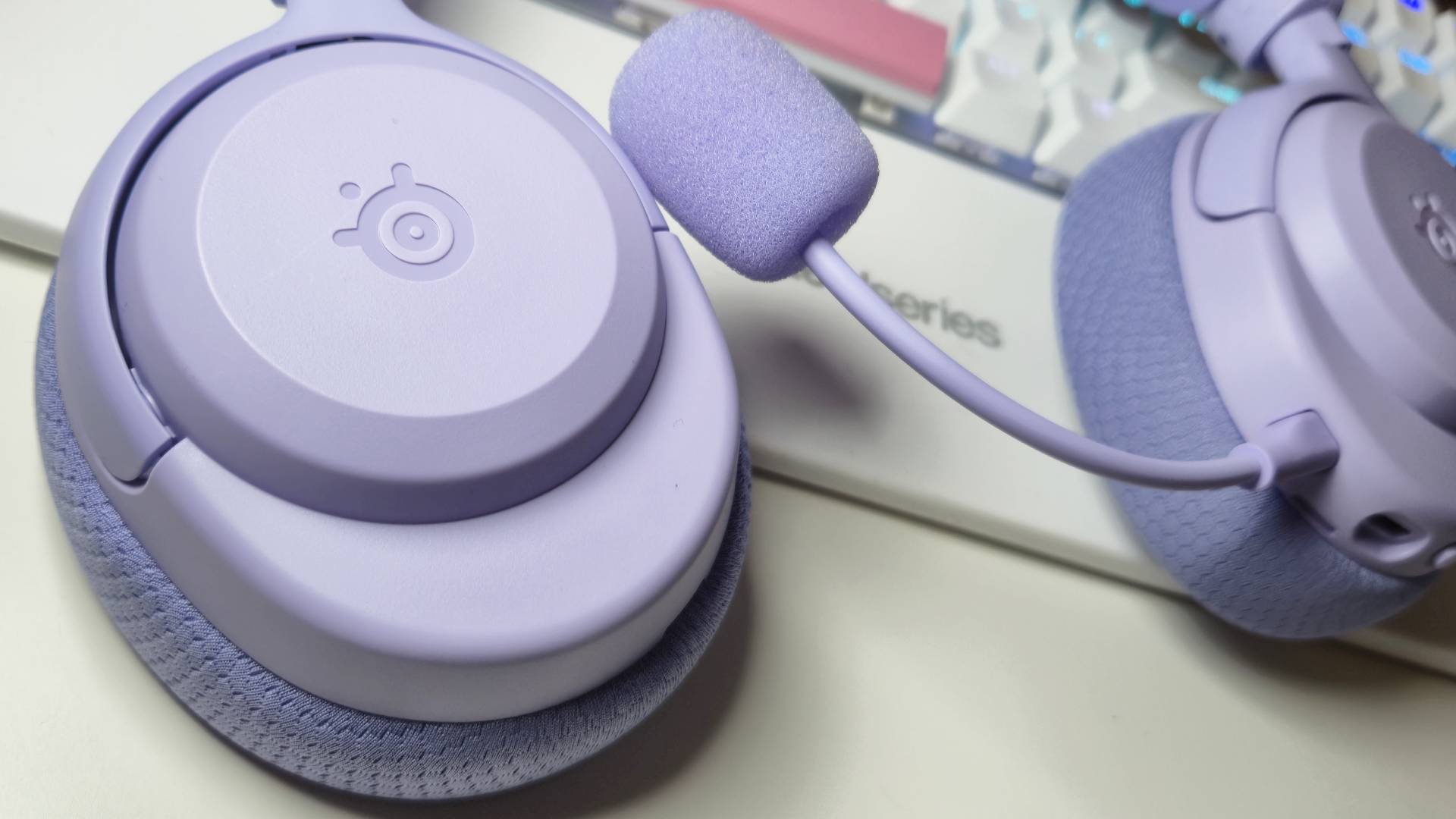 Photos of the SteelSeries Arctis Nova 3 Wireless gaming headset in Lavender, taken by writer Rosalie Newcombe, on a white desk.