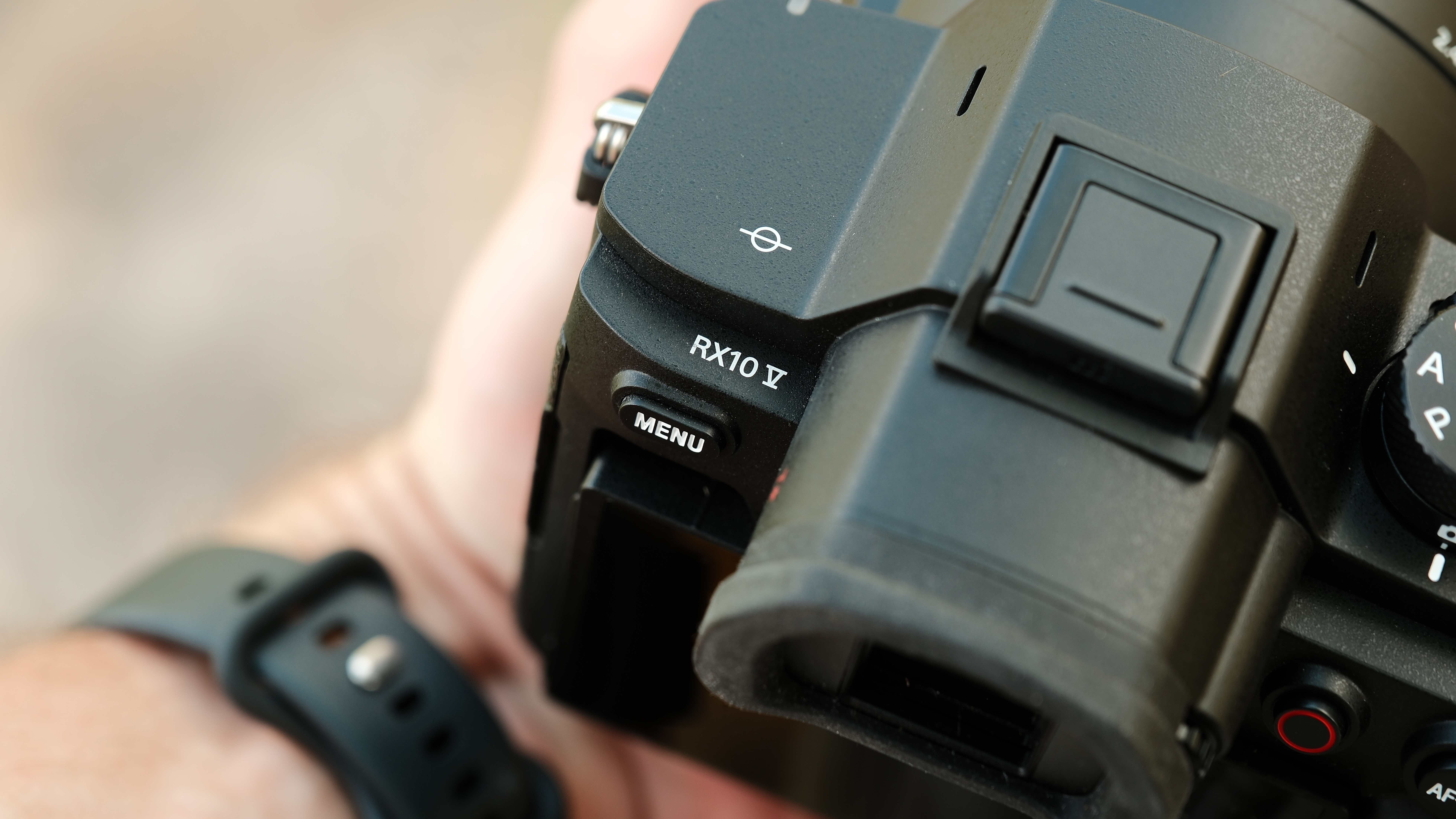 Close-up of the Sony RX10 V model badge, menu button, hot shoe, and electronic viewfinder.