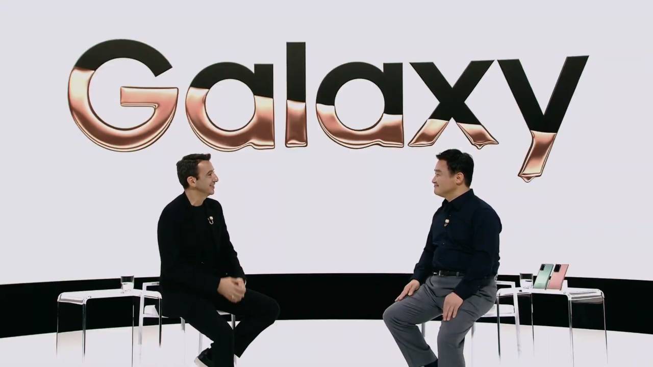 Two people talking in front of a white Galaxy sign