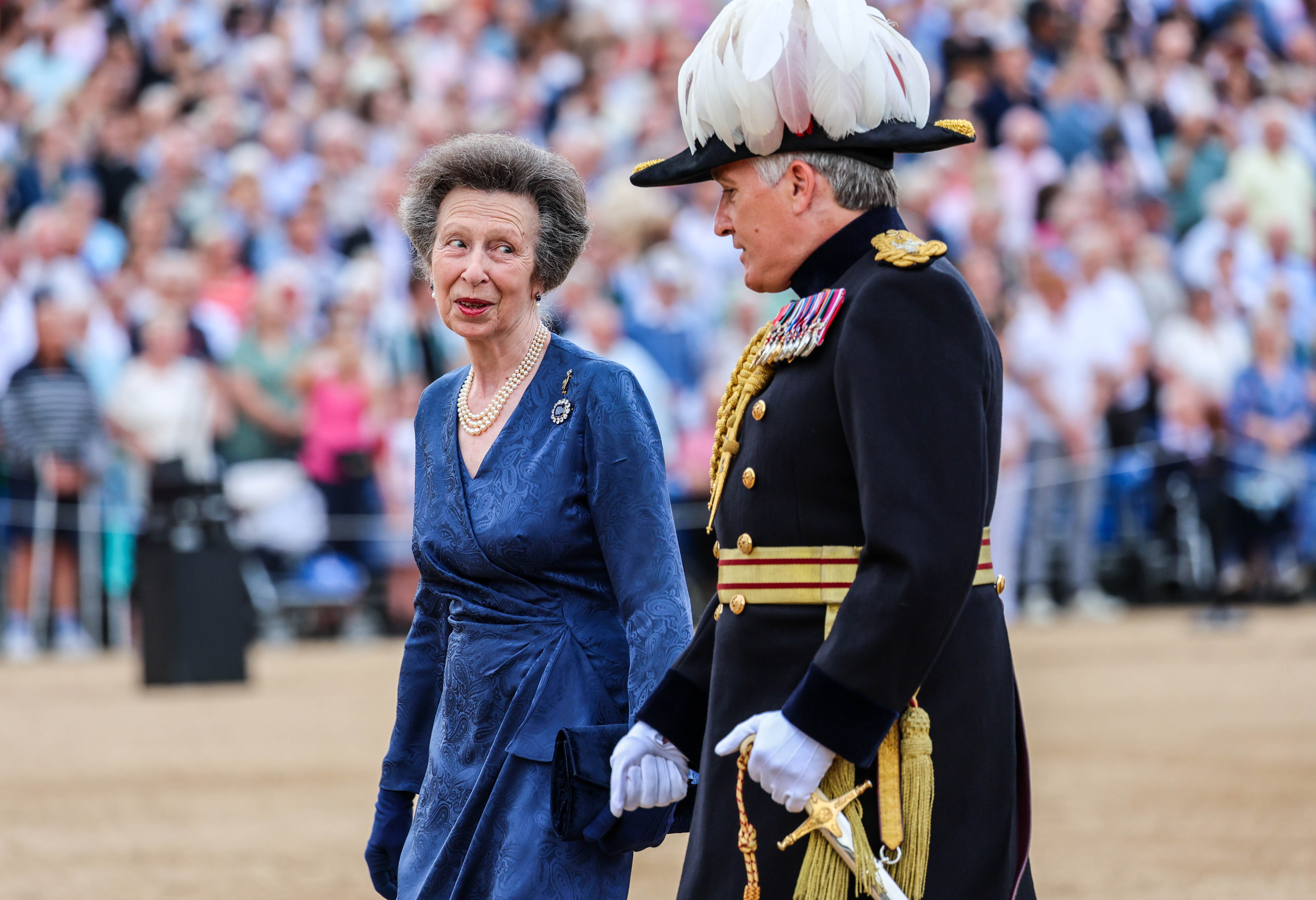 Princess Anne wearing a blue wrap dress talking to a soldier