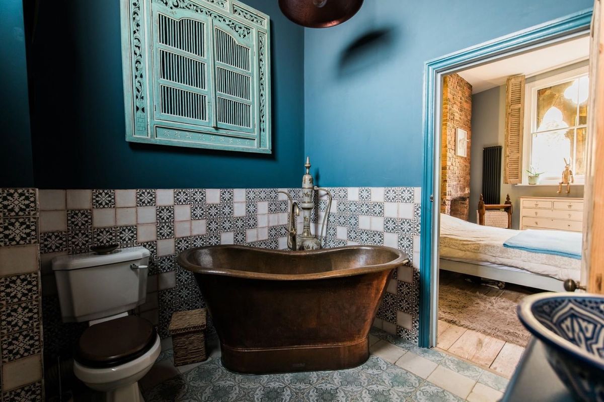 A copper bath connected to the bedroom and green patterned tiles