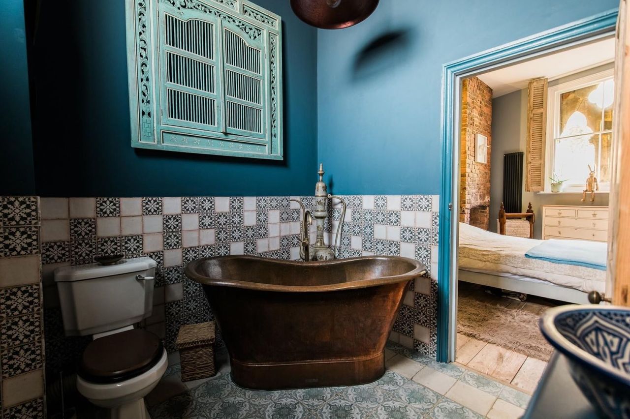 A copper bath connected to the bedroom and green patterned tiles