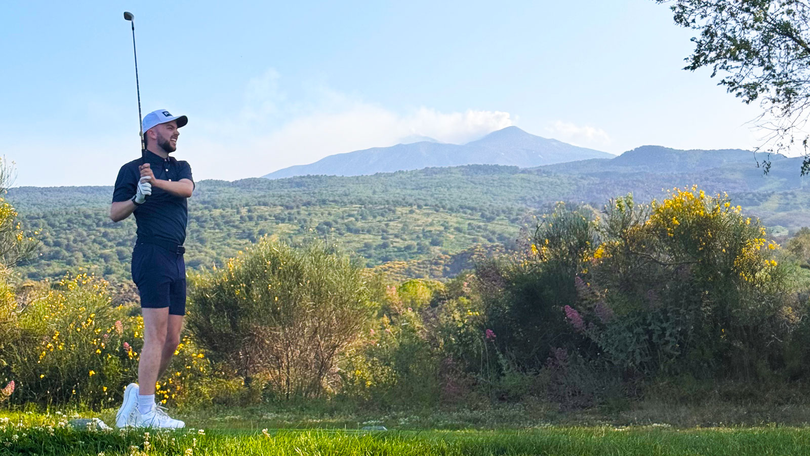 Dan Parker hitting a golf shot with Mount Etna in the background
