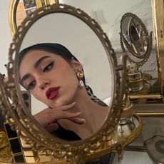 Woman wearing red lipstick looking into a mirror