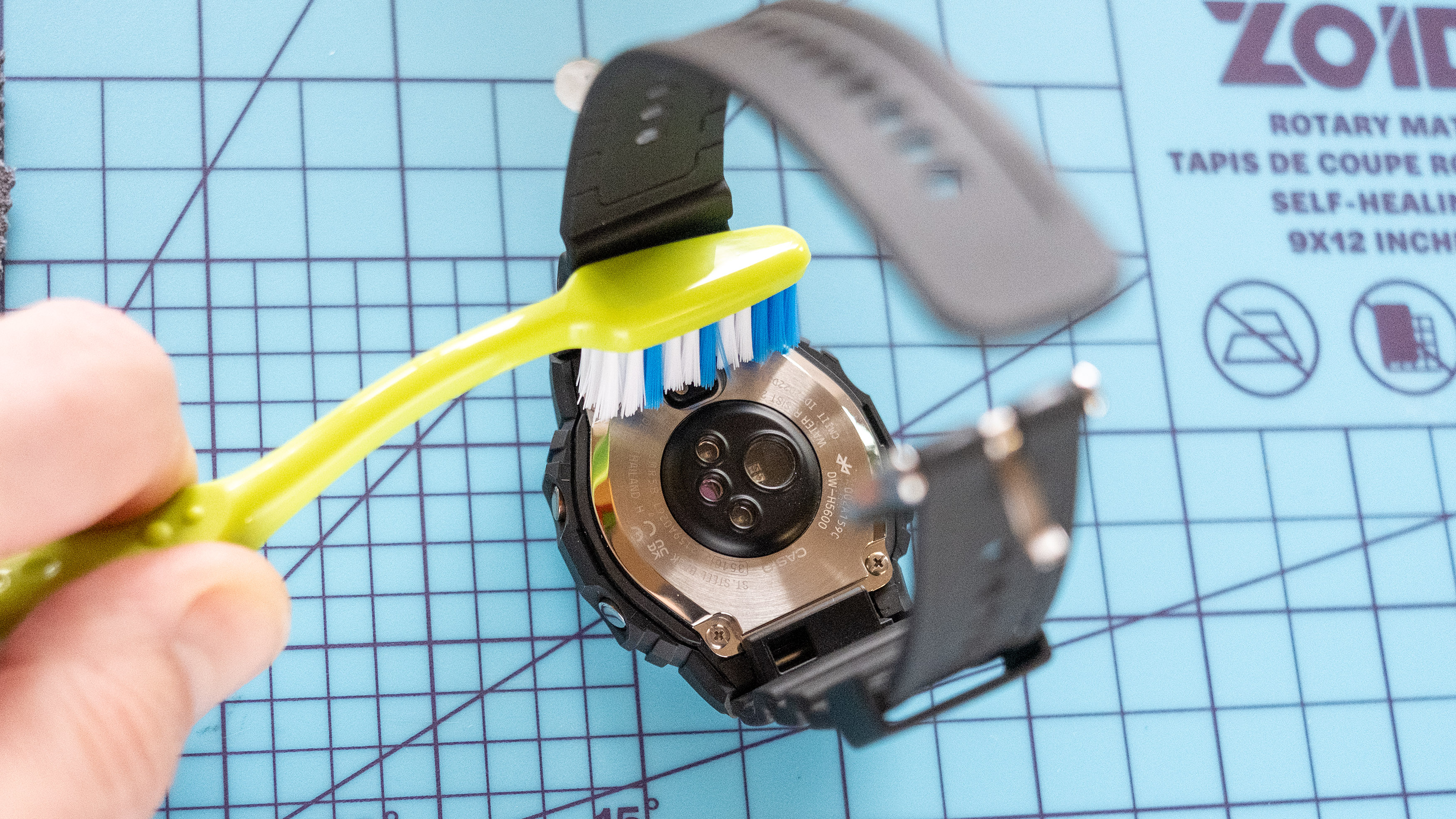 فرك الجزء الخلفي من ساعة اللياقة البدنية G-Shock باستخدام فرشاة أسنان.