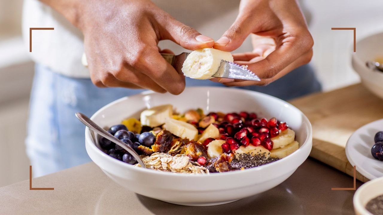 Woman cutting banana onto bowl of porridge, one of the meals to eat if you&#039;re wondering how many calories should I eat for breakfast