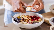 Woman cutting banana onto bowl of porridge, one of the meals to eat if you're wondering how many calories should I eat for breakfast