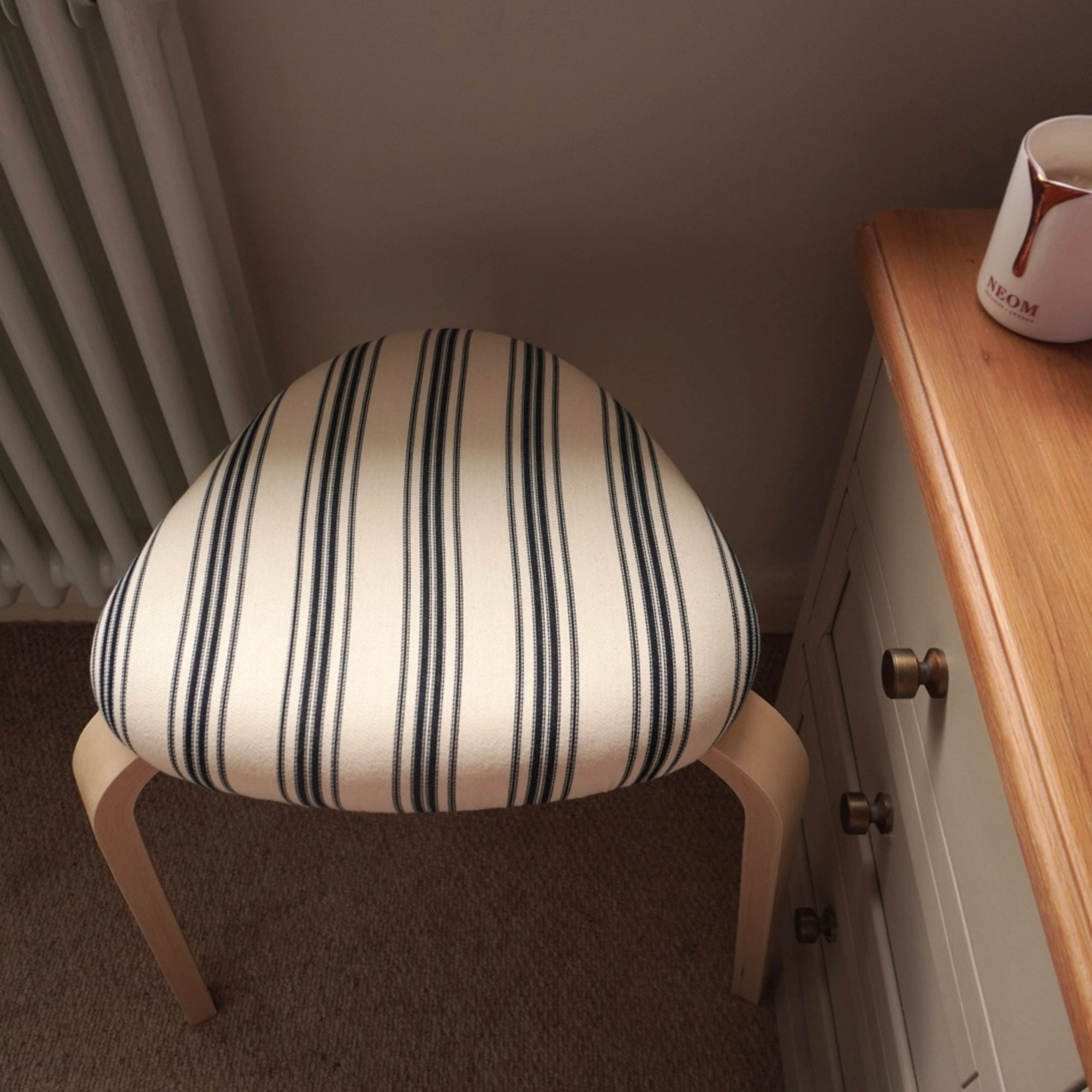 AI image of wooden stool with striped upholstered cushion
