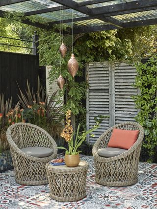 Rattan bistro set on a patterned patio underneath a covered pergola