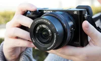 A pair of hands holding the Sony a6000, another of the best mirrorless cameras