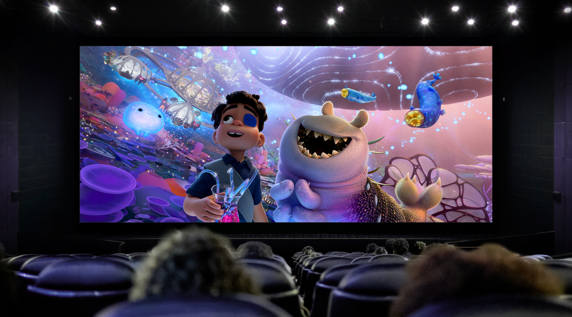 A cinema screen with Pixar's upcoming animated feature, Elio, on screen watched by a seated crowd.