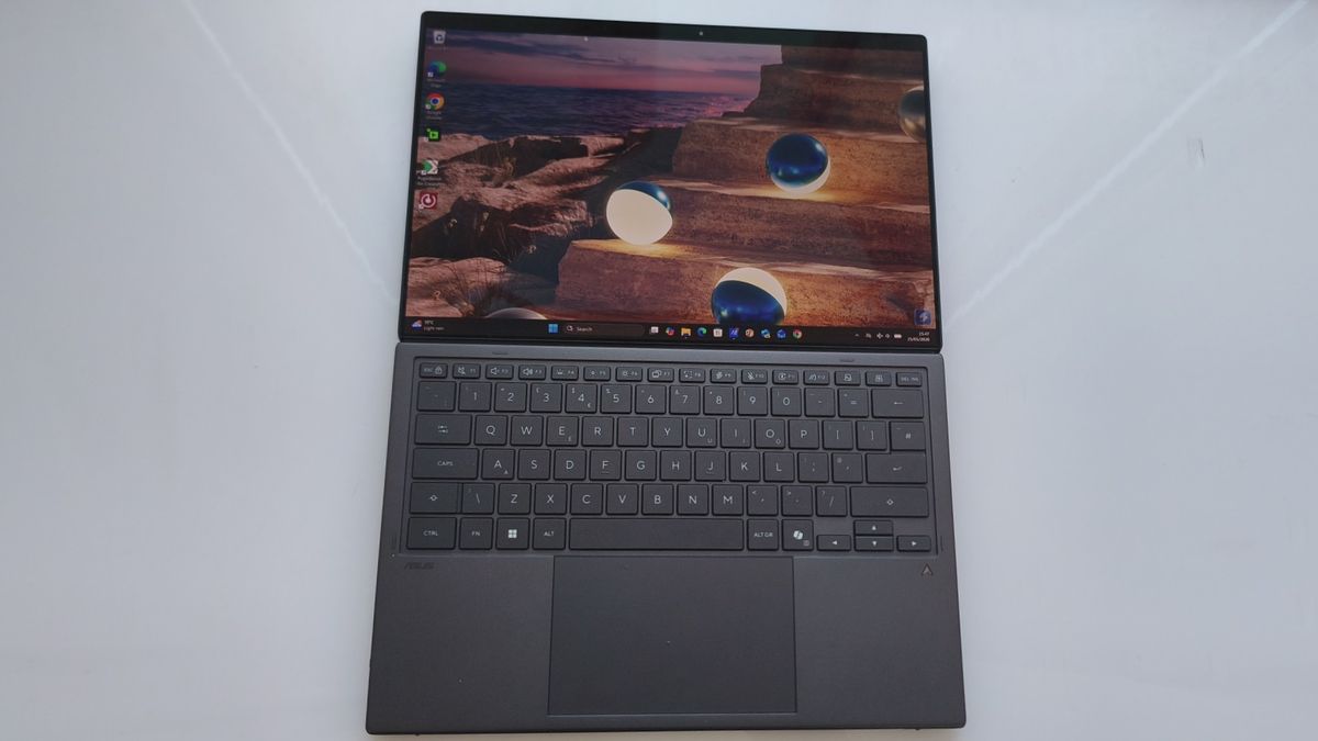 The ASUS Zenbook Duo opened completely flat at a 180-degree angle on a white surface, with the wireless keyboard placed directly over the lower secondary screen.