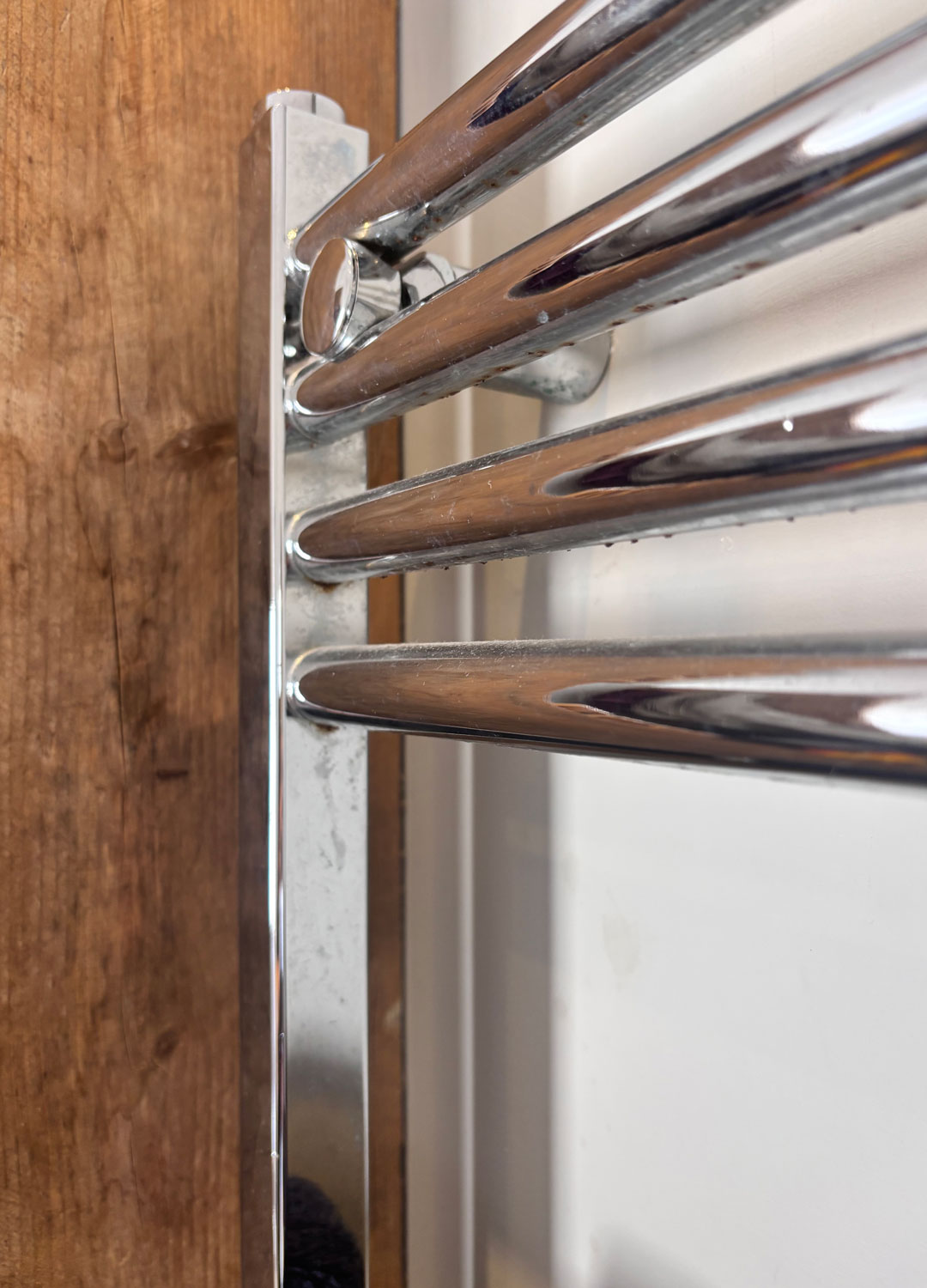 close up of chrome heated towel rail with rust and smears