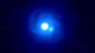 This Hubble Space Telescope image of gravitational lens B0218+357 reveals two bright sources separated by about a third of an arcsecond, each an image of the background blazar. Spiral arms belonging to the lensing galaxy also can be seen. B0218+357 boasts the smallest separation of lensed images currently known.
