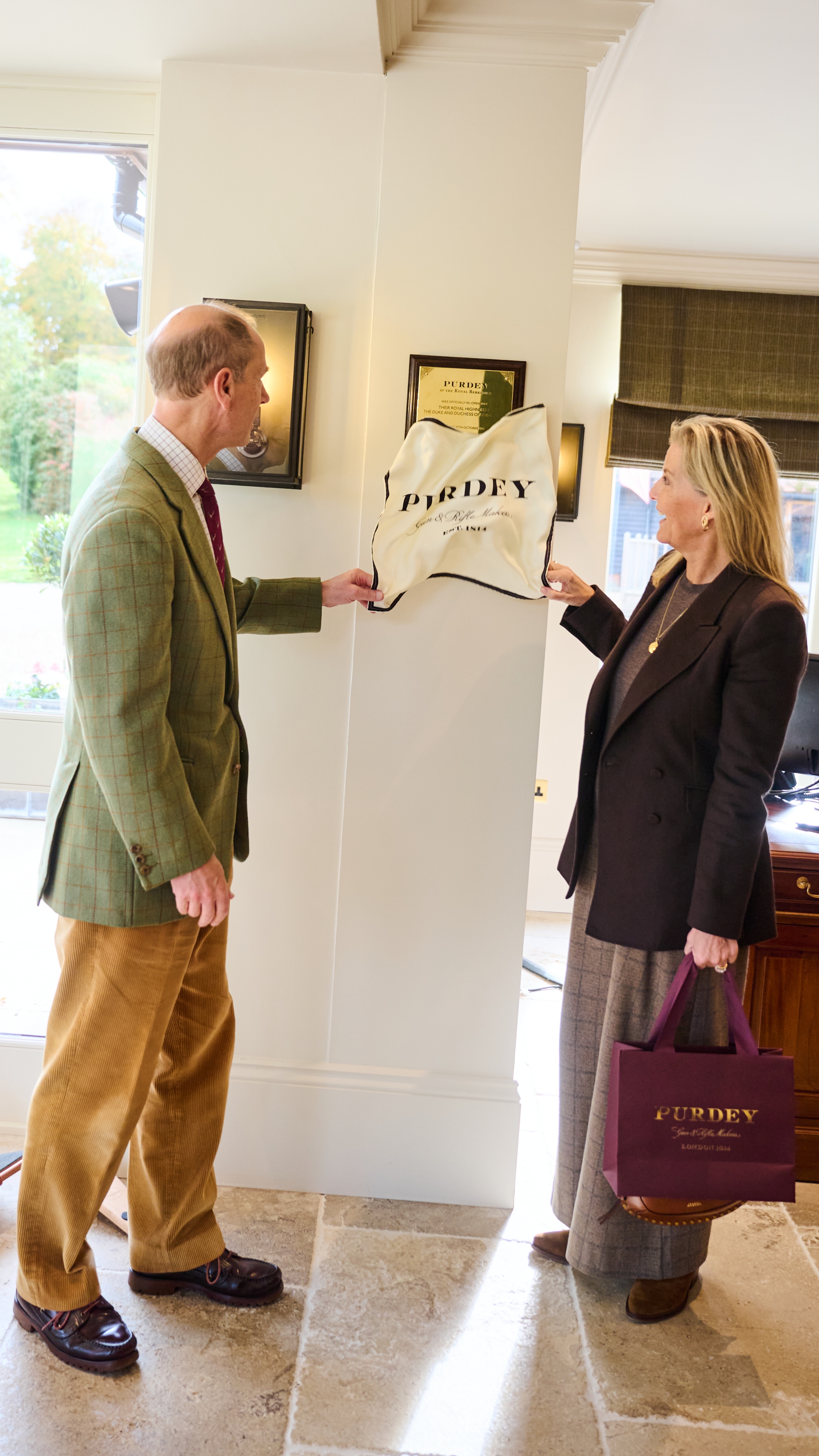 Duke and Duchess of Edinburgh smile as they jointly unveil a plaque at Purdey At the Royal Berkshire shooting school