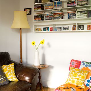 living room with shelving and books with flower on vase and floor lamp