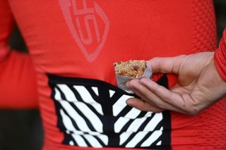 Male cyclist pulling a homemade apple crumble bar out of his cycling jersey pocket on a bike ride