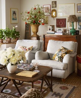 neutral cottage living room with two printed armchairs and an eclectic gallery wall with lots of floral arrangements around the room