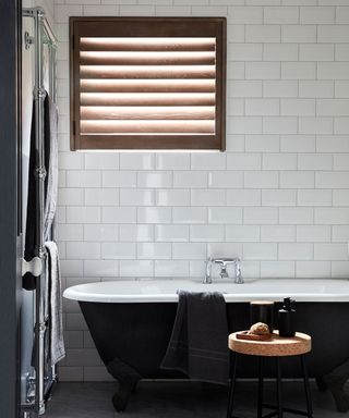 mono bathroom with black bath and wooden window shutters