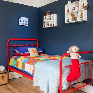 children room with navy wall and pillows on red coloured bed