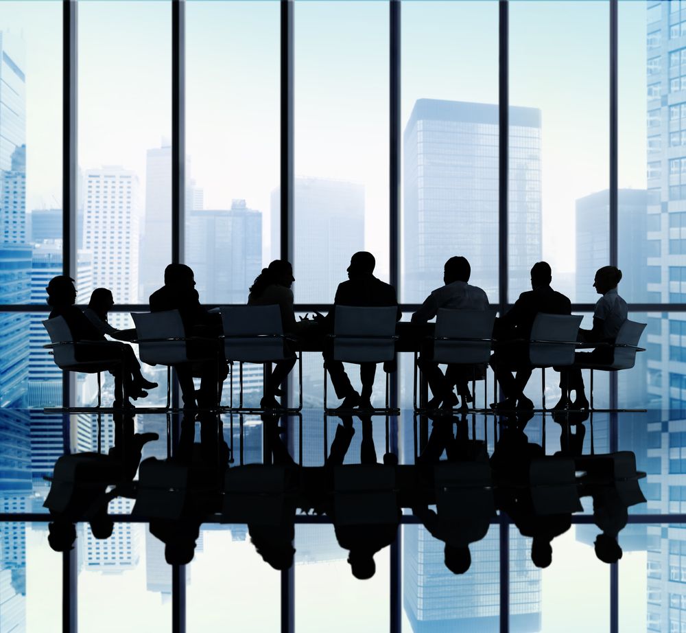 boardroom filled with people&amp;#039;s silhouettes sat around a large table