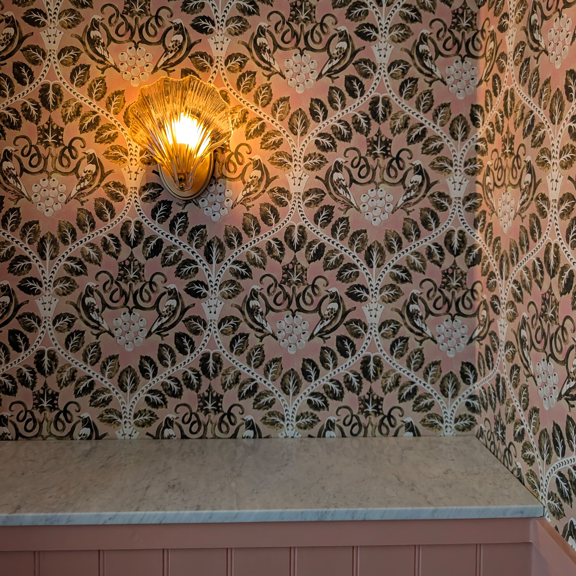 Scalloped glass sconce on pink patterned wallpaper
