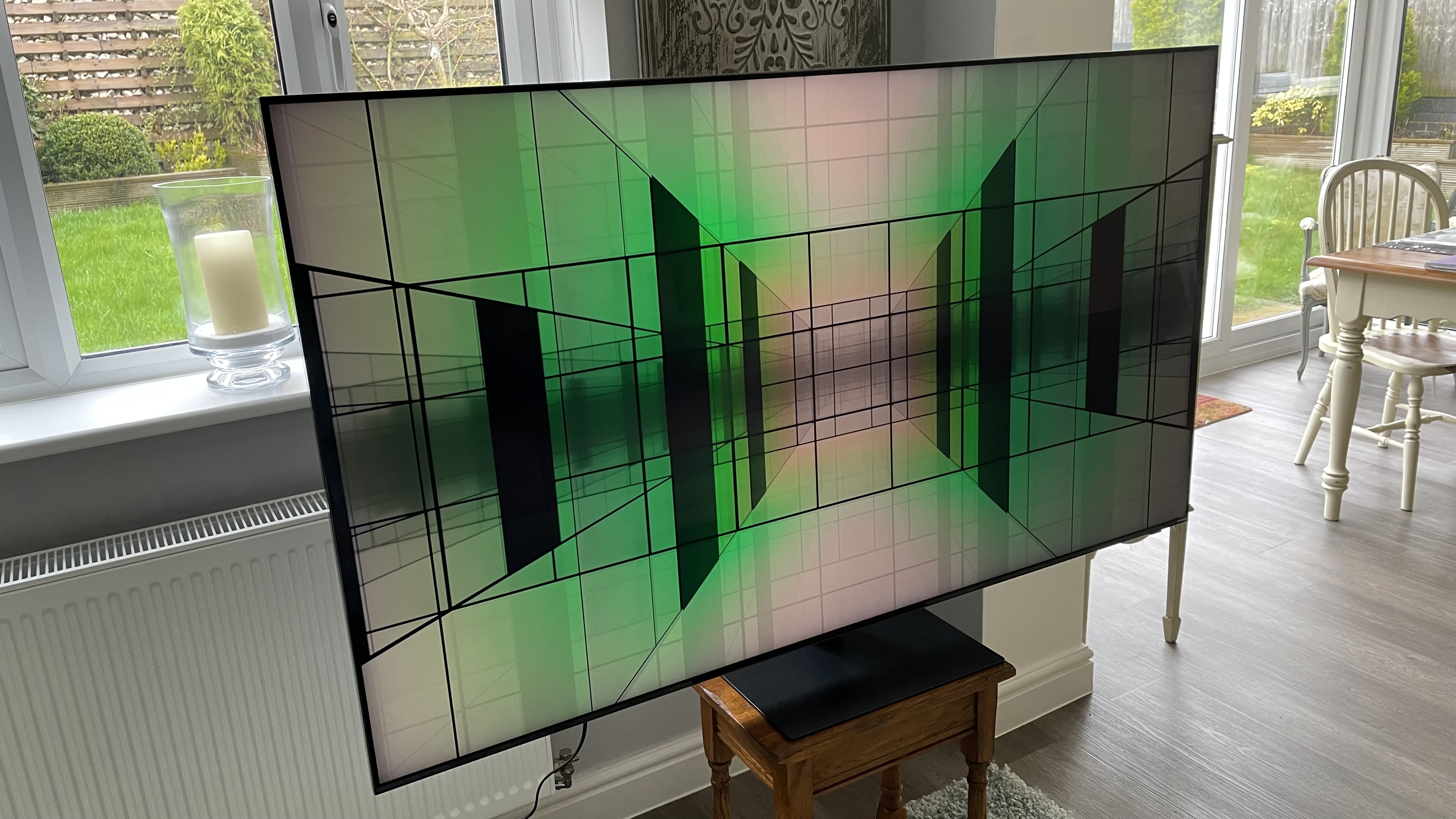 Samsung S95C OLED TV on stand showing abstract  image  onscreen
