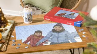An almost-completed jigsaw puzzle features two small children playing in the snow.