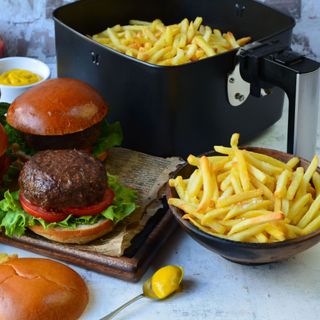 black air fryer in kitchen with burgers and fries