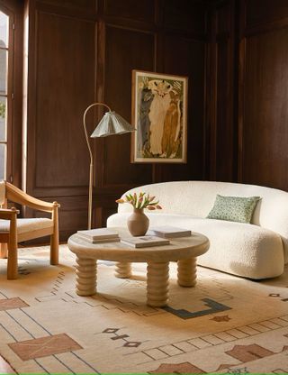 dark wood living room with a white couch, a floor lamp, and a round coffee table with chunky legs